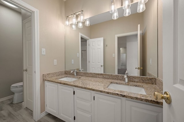 full bathroom with a sink, toilet, and double vanity