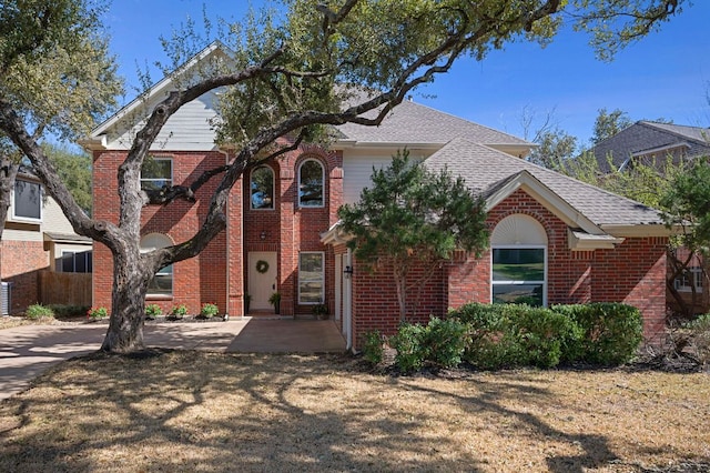 view of front of property with a shingled roof and brick siding