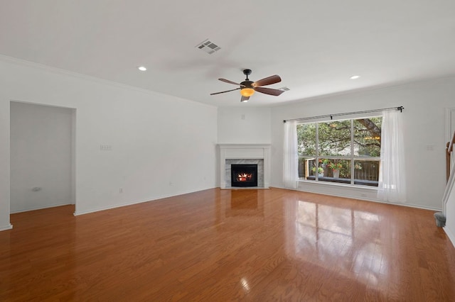 unfurnished living room featuring a high end fireplace, visible vents, crown molding, and wood finished floors