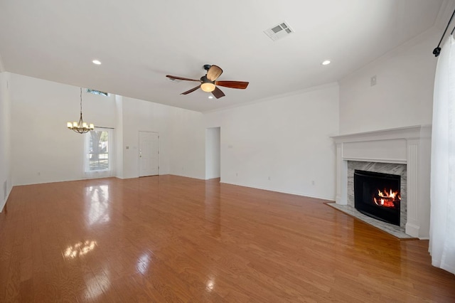 unfurnished living room with recessed lighting, ceiling fan with notable chandelier, a fireplace, visible vents, and light wood-style floors