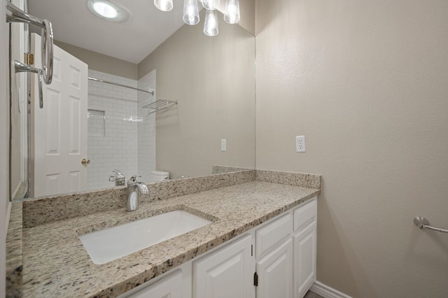 bathroom featuring a shower, baseboards, vanity, and toilet