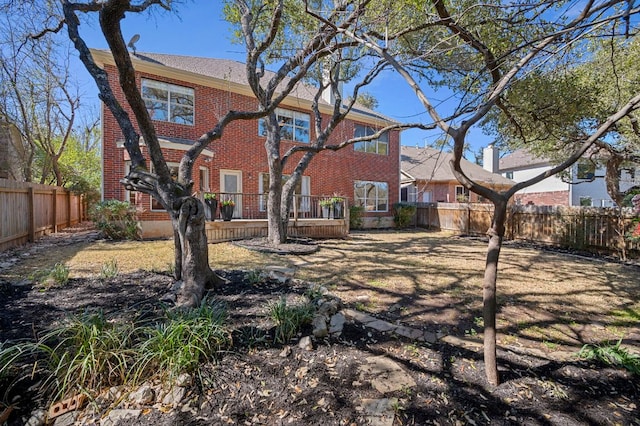 rear view of property featuring brick siding, a fenced backyard, and a wooden deck