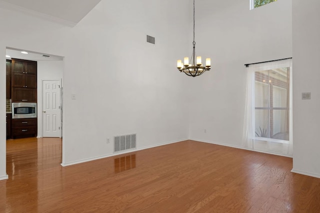 interior space featuring visible vents, light wood-style flooring, and a high ceiling