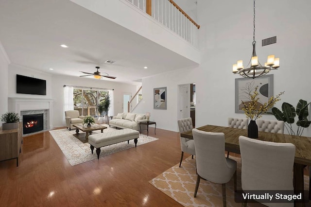 living area with ceiling fan with notable chandelier, a fireplace, wood finished floors, and visible vents