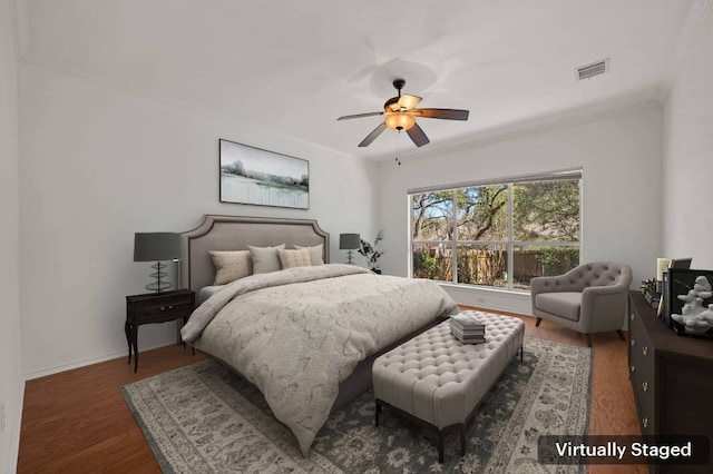 bedroom with crown molding, visible vents, a ceiling fan, wood finished floors, and baseboards