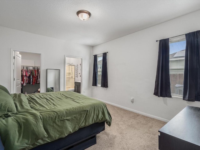 carpeted bedroom with baseboards, connected bathroom, a spacious closet, a textured ceiling, and a closet