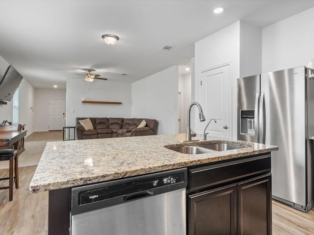 kitchen featuring stainless steel appliances, visible vents, a sink, an island with sink, and light wood-type flooring