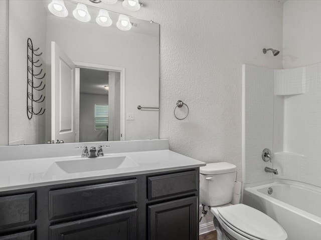 bathroom with toilet, shower / bathtub combination, a textured wall, and vanity