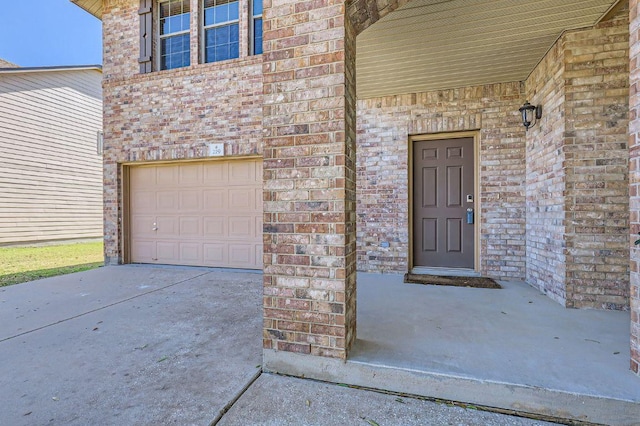 property entrance featuring a garage and brick siding