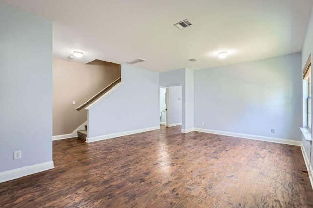 unfurnished living room featuring wood finished floors, visible vents, baseboards, and stairs