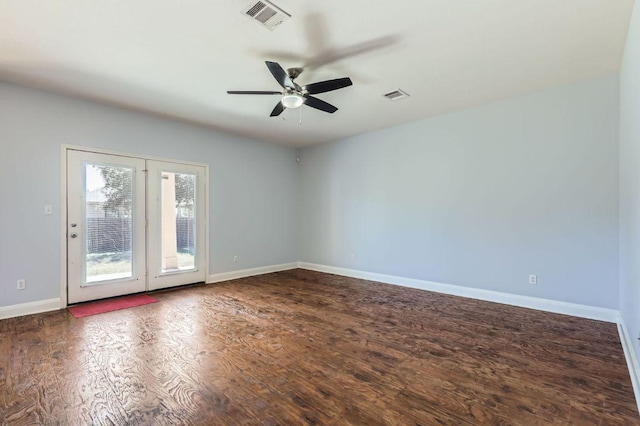 spare room with dark wood-style floors, visible vents, baseboards, and a ceiling fan