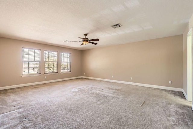 spare room featuring baseboards, visible vents, a ceiling fan, and light colored carpet