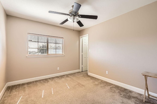 empty room with carpet flooring, a ceiling fan, and baseboards