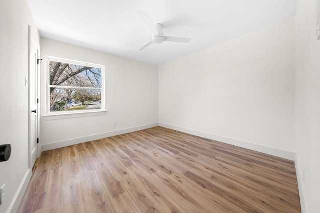 spare room featuring ceiling fan, light wood finished floors, and baseboards