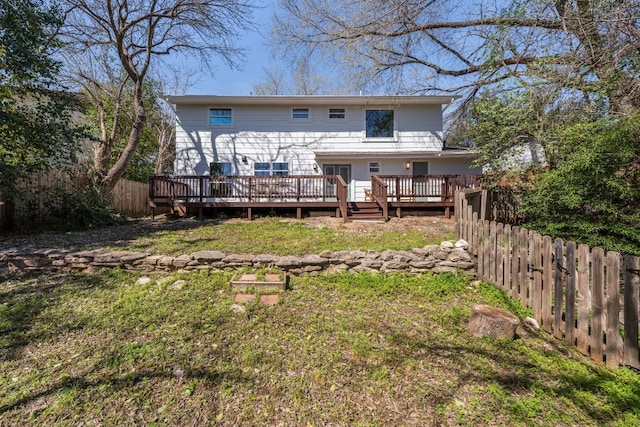 rear view of house featuring fence private yard, a lawn, and a wooden deck