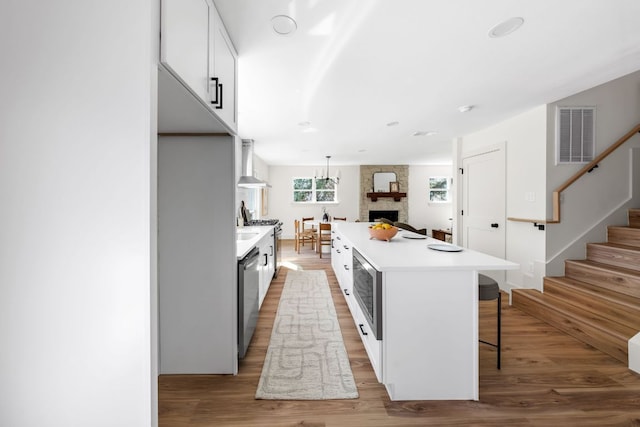 kitchen featuring visible vents, a kitchen island, appliances with stainless steel finishes, light wood-type flooring, and a kitchen bar