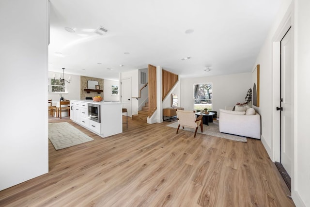 living room featuring stairway, light wood-style flooring, and visible vents