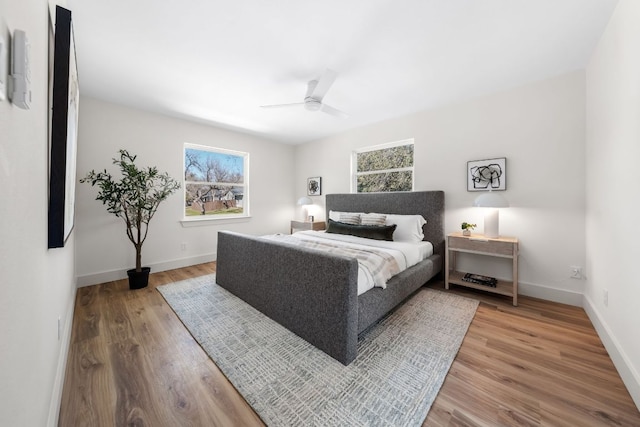 bedroom featuring ceiling fan, baseboards, and wood finished floors