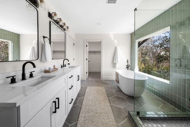 bathroom with tile patterned flooring, a sink, visible vents, a soaking tub, and double vanity