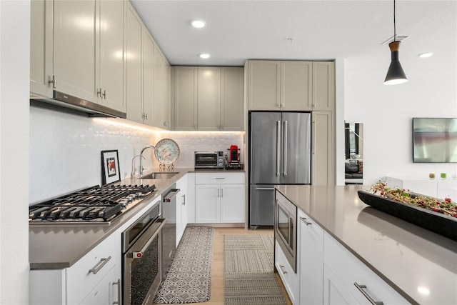 kitchen with tasteful backsplash, a toaster, stainless steel appliances, under cabinet range hood, and a sink