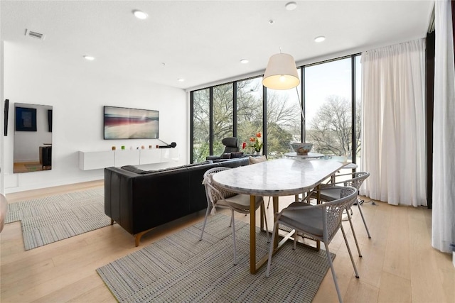 dining room with light wood finished floors, visible vents, and a healthy amount of sunlight