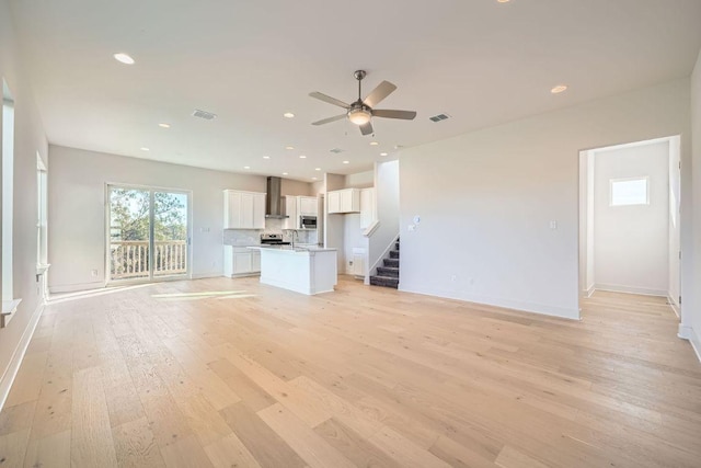 unfurnished living room featuring recessed lighting, visible vents, baseboards, stairs, and light wood finished floors