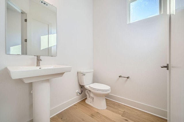 bathroom with baseboards, visible vents, toilet, and wood finished floors