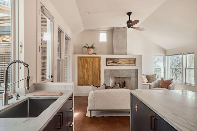 sitting room featuring a large fireplace, ceiling fan, baseboards, and vaulted ceiling