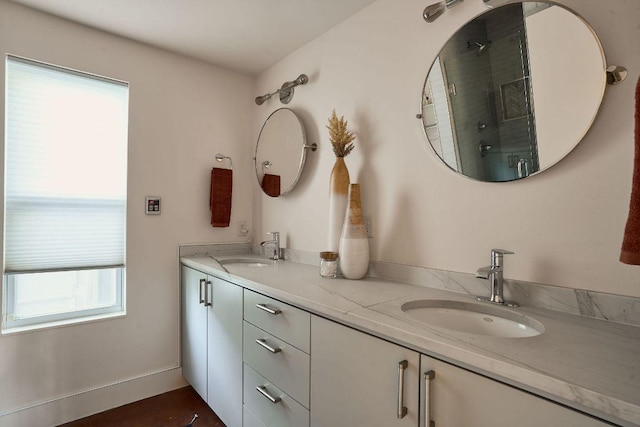 full bath featuring double vanity, an enclosed shower, a sink, and baseboards