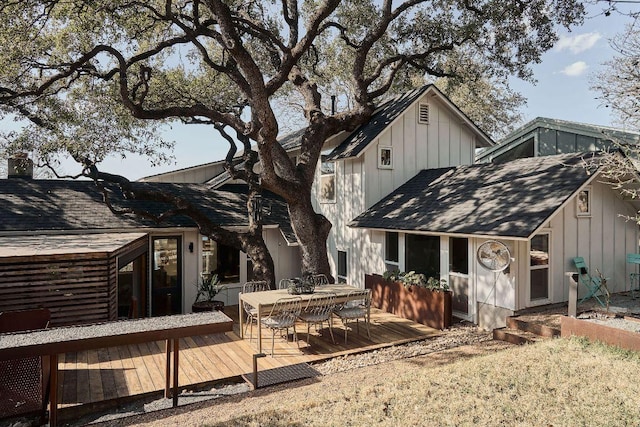 rear view of property featuring a shingled roof, a deck, and board and batten siding