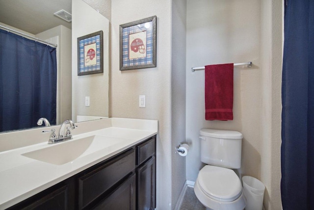 bathroom with toilet, vanity, and visible vents