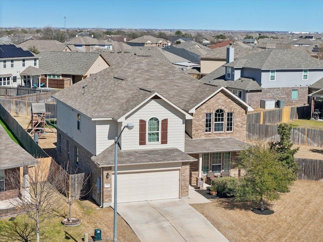 traditional-style home featuring a garage, concrete driveway, a residential view, roof with shingles, and fence