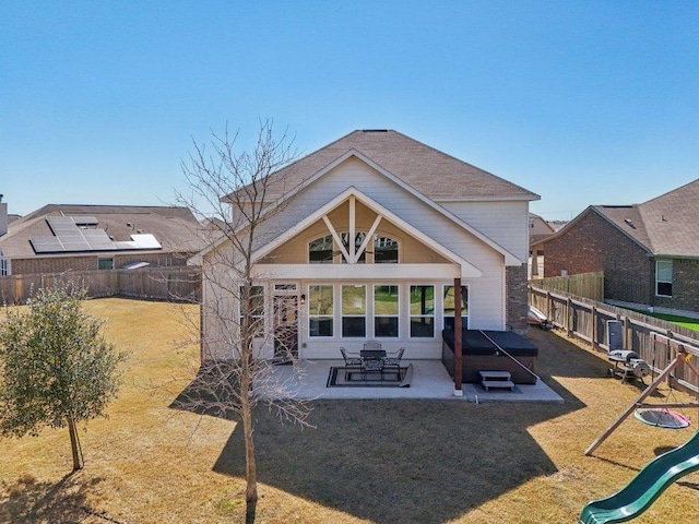 rear view of property featuring a patio, a yard, a playground, and a fenced backyard