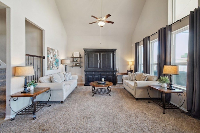 carpeted living area with high vaulted ceiling, ceiling fan, stairway, and baseboards