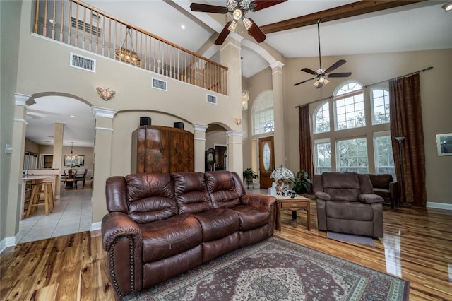 living room with visible vents, arched walkways, wood finished floors, and decorative columns