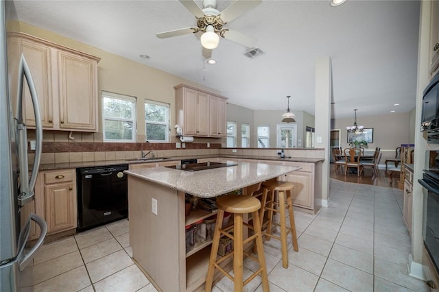 kitchen featuring black appliances, light tile patterned flooring, a kitchen island, and a healthy amount of sunlight