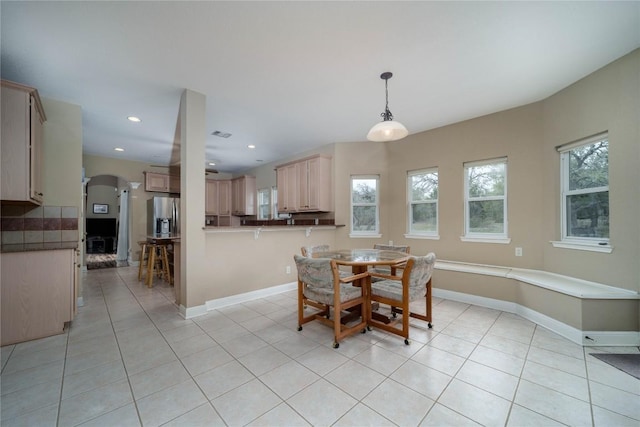 dining space featuring arched walkways, baseboards, and light tile patterned floors