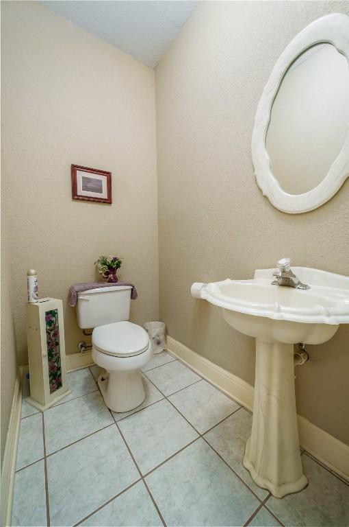 bathroom with tile patterned flooring, baseboards, and toilet