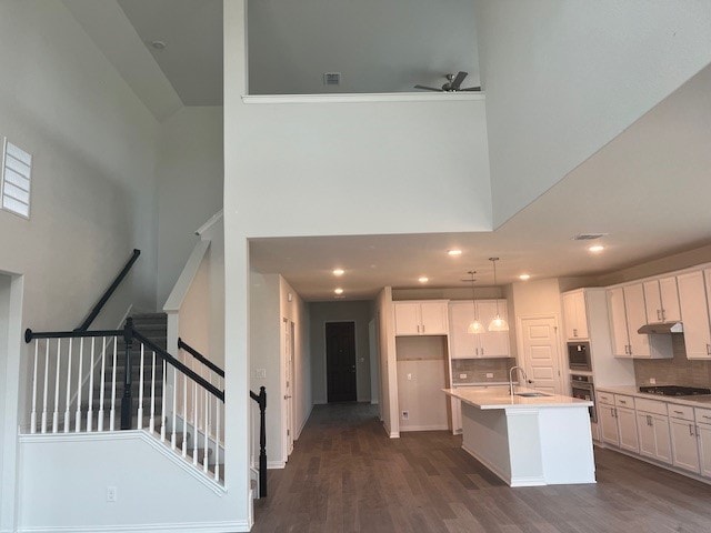 503 Ansley Ct, Taylor, TX 76574 - kitchen with a towering ceiling, stainless steel oven, white cabinets, under cabinet range hood, and a ceiling fan