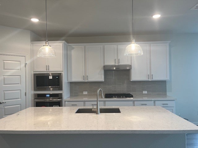 503 Ansley Ct, Taylor, TX 76574 - kitchen with appliances with stainless steel finishes, a sink, under cabinet range hood, white cabinetry, and recessed lighting