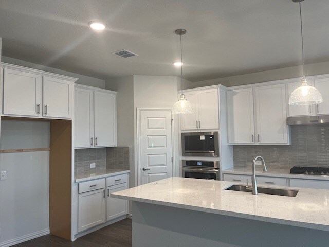 503 Ansley Ct, Taylor, TX 76574 - kitchen with appliances with stainless steel finishes, a sink, under cabinet range hood, white cabinetry, and recessed lighting