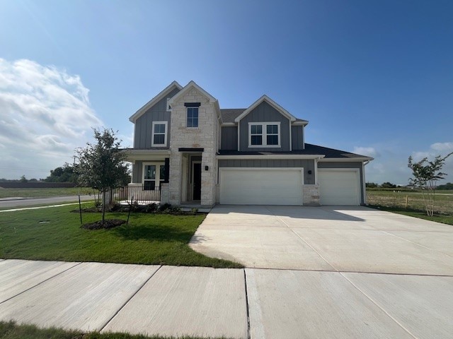 503 Ansley Ct, Taylor, TX 76574 - view of front of home with board and batten siding, stone siding, a front lawn, and concrete driveway