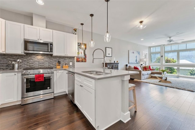 kitchen with stainless steel appliances, a peninsula, a sink, and decorative backsplash