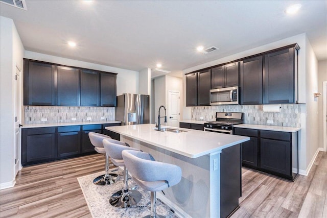 kitchen featuring light wood finished floors, visible vents, appliances with stainless steel finishes, light countertops, and a sink