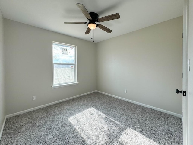 carpeted spare room featuring a ceiling fan and baseboards