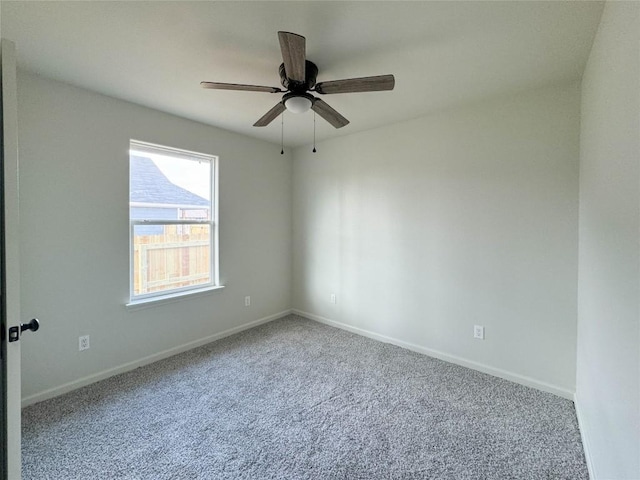 carpeted spare room with a ceiling fan and baseboards