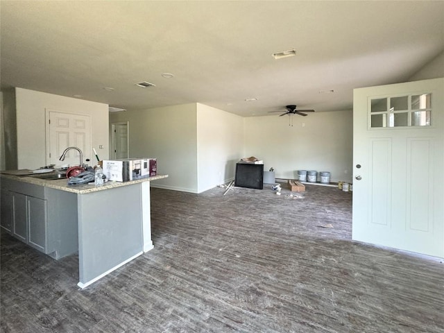 kitchen with ceiling fan, a sink, visible vents, dark wood finished floors, and a center island with sink