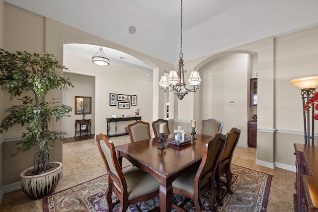 dining area with an inviting chandelier, baseboards, and arched walkways