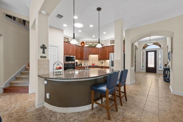 kitchen with visible vents, decorative backsplash, arched walkways, appliances with stainless steel finishes, and a sink