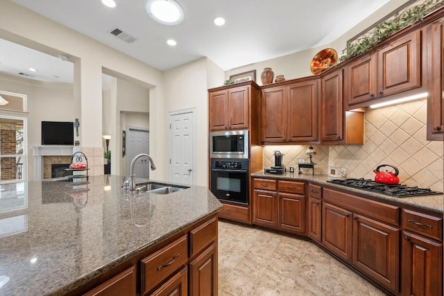 kitchen with black appliances, visible vents, dark stone counters, and a sink